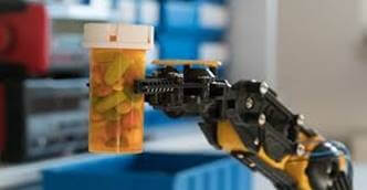 Robot arm moving jar of medical capsules