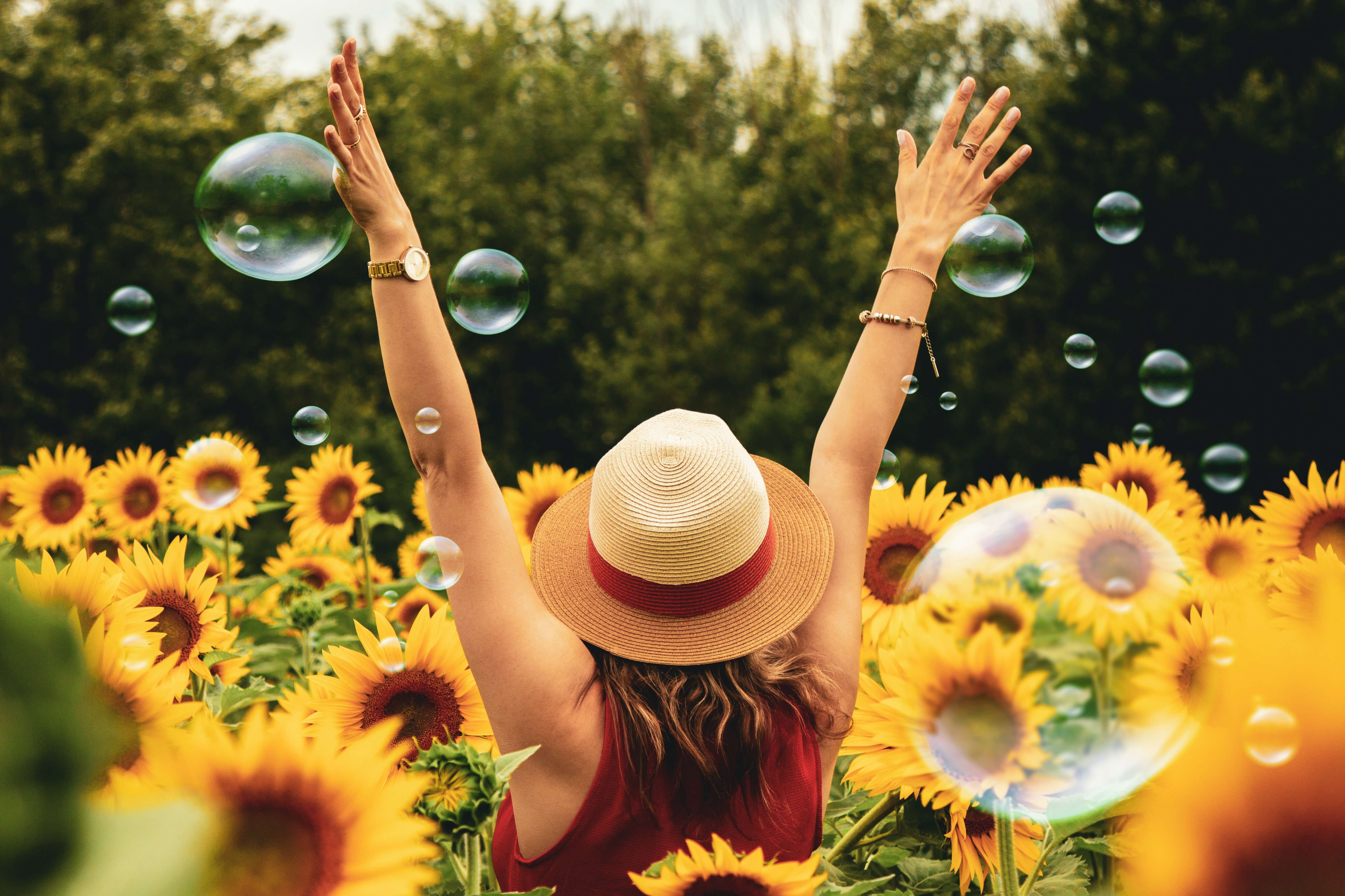 Happy woman in field of sunflowers with bubbles